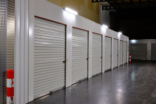 Row of white doors indoor storage units in a self storage facility. Rental Storage Units with red white safety pole. Netherlands