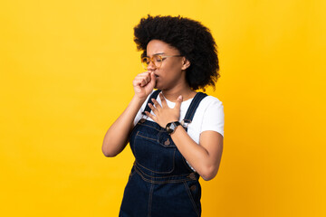Young African American woman isolated on yellow background coughing a lot