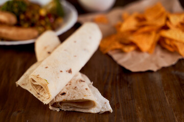 Twisted in a pita bread roll lie on a wooden table. Close-up