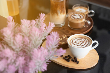 Cup of latte art, brownies, coffee beans on a wooden plate, ice coffee place on the black top table