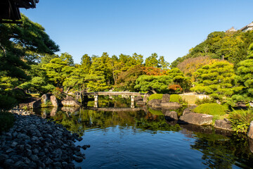 Koko-en traditional japanese garden with a pond reflecting trees and colorful autumn trees in Himeji Castle, Japan.