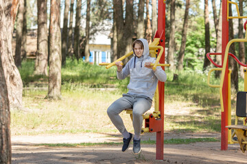 Single young man doing exercises on the sports ground in the park, street workout. Fitness outside. Exercising alone for Covid-19 revention