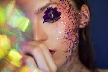 Beautiful young girl with luxurious brilliant purple make-up on a blue background. Good for beauty salons, banners, posters, flyers.