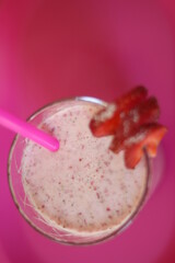 Delicious cocktail made of milk, fresh, red strawberries in glass. Pink background. Healthy food in Summer.