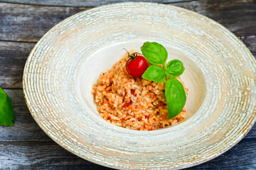Home made italian oven baked tomato risotto  with a fresh leaf of basil and parmesan cheese 