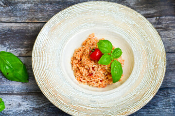 Home made italian oven baked tomato risotto  with a fresh leaf of basil and parmesan cheese 
