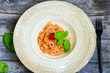 Home made italian oven baked tomato risotto  with a fresh leaf of basil and parmesan cheese 