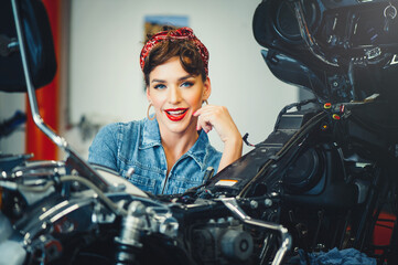 beautiful girl posing repairs a motorcycle in a workshop, pin-up style, service and sale