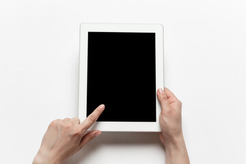 Close up of human hands using tablet isolated on white background. Top view. Copyspace, blank screen. Surfing, online shopping, scrolling, betting, working. Education and business concept.