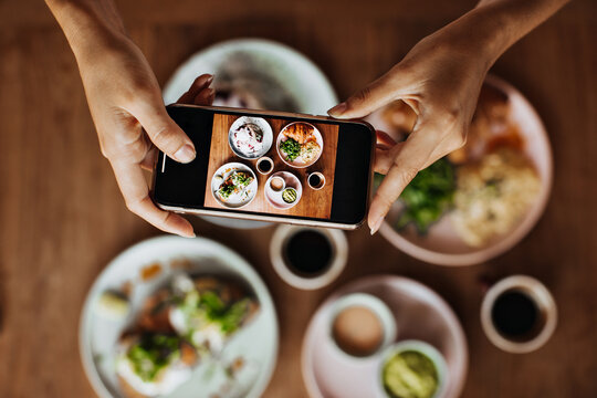 Photo of female hands holding phone and taking pictures of tasty food. Flat-lay. Snapshot of plate with colorful meal
