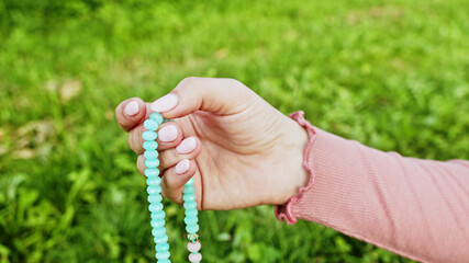 Woman lit hand close up counts rosary - malas strands of gemstones beads used for keeping count...