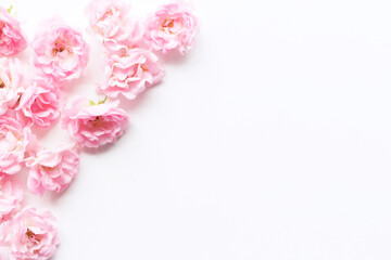 Obraz na płótnie Canvas Styled stock photo. Spring feminine scene, floral composition. Decorative banner, corner made of beautiful pink roses. White table background. Flat lay, top view.