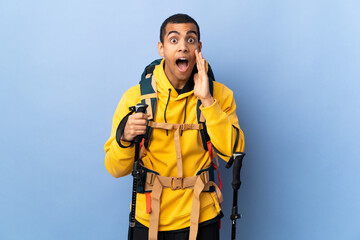 African American man with backpack and trekking poles over isolated background with surprise and shocked facial expression