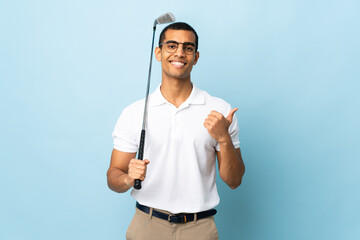Fototapeta premium African American man over isolated blue background playing golf and with thumbs up because something good has happened