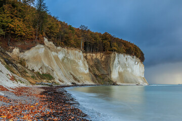 Autumn mood on the Baltic Sea. Stony beach on the coastline on the island of Rügen. Chalk cliffs in the morning at sunrise. Trees with foliage in the Jasmund National Park on the Baltic Sea