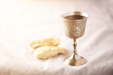 Unleavened bread, chalice of wine, silver kiddush wine cup on canva background. Communion still...