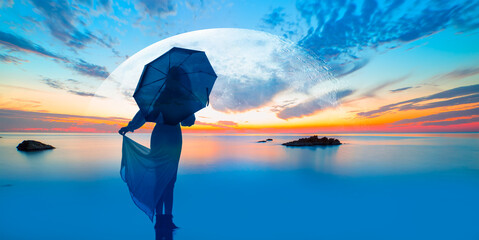 Young girl in dress holding umbrella and walking on the calm sea -  Long exposure image of dramatic...