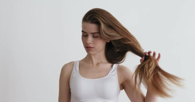 Young confident woman doing long hair style looking in mirror