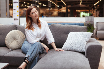 Charming woman sitting on a new couch at furniture store