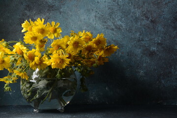 Bouquet of Doronicumflowers ( sunflower family )in a transparent glass flower vase.