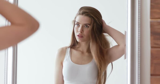 Beautiful woman enjoying her appearance, looking at mirror