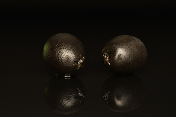Pickled spicy black olives, close-up, on a black background.