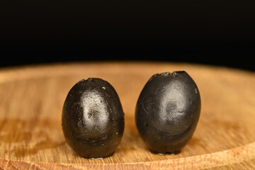 Pickled spicy black olives, close-up, on a black background.