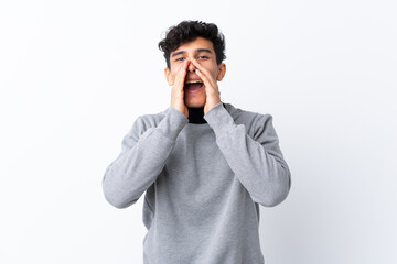 Young Argentinian man over isolated white background shouting and announcing something