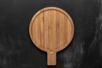 round wooden cutting board in the middle of a gray background. free space for your text, top view