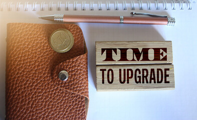 time to upgrade text on a wooden blocks, brown leather wallet, coins and pen put on copybook....