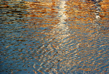 Reflections in the rippled waters of a harbor make a natural abstract in fall colors of brown, gpld and blue.