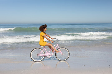 Mixed race woman riding bike on the beach