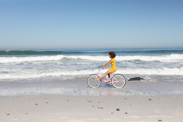 Fototapeta premium Mixed race woman riding bike on the beach
