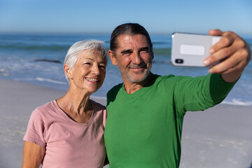 Senior Caucasian couple taking a selfie at the beach.