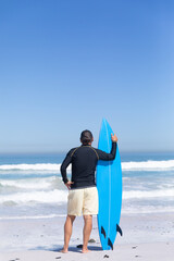 Senior Caucasian man holding a surfboard at the beach.