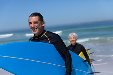 Senior Caucasian couple holding surfboards at the beach.