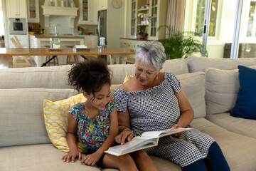 Senior mixed race woman reading with her granddaughter