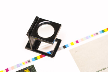 Photo session at an offset press. Printing in ink with CMYK, cyan, magenta, yellow and black. Graphic arts, offset printing. Thread counting adjustment tool