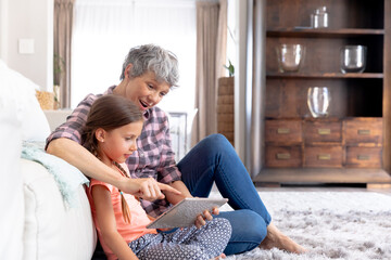 Senior Caucasian woman using a tablet at home with her granddaughter