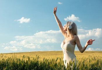 Blonde woman in headphones dancing in wheat field in summer time