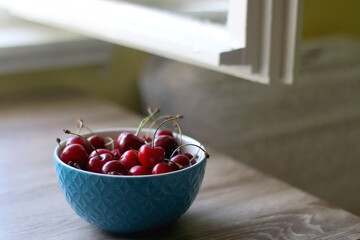 Bowl of cherries on a table indoor. Selective focus.