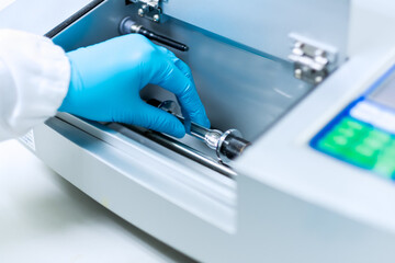 Analyst is placing the sample solution for test of specific rotation by automatic polarimeter in the laboratory, concept of chemical laboratory in pharmaceutical industry, selective focus photograph. - obrazy, fototapety, plakaty