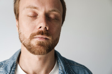 Obraz premium Photo of caucasian young man posing with eyes closed on camera