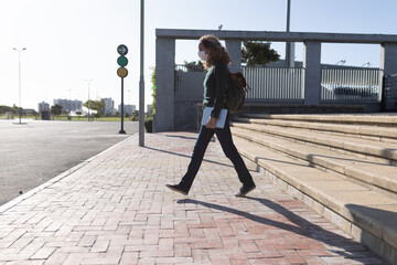 Caucasian woman wearing a protective mask and walking in the streets