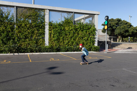 Caucasian woman wearing a protective mask and skating in the streets