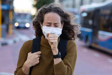 Caucasian woman wearing a protective mask and coughing out in the streets
