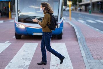 Caucasian woman wearing a protective mask and using her phone in the streets