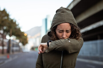 Fototapeta premium Caucasian woman coughing and wearing a smartwatch in the streets