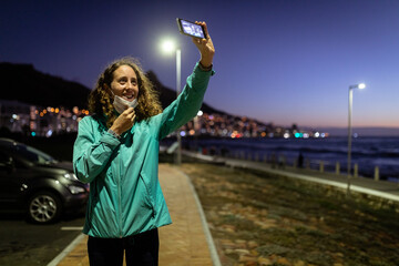 Caucasian woman putting off a protective mask, taking a picture in the streets