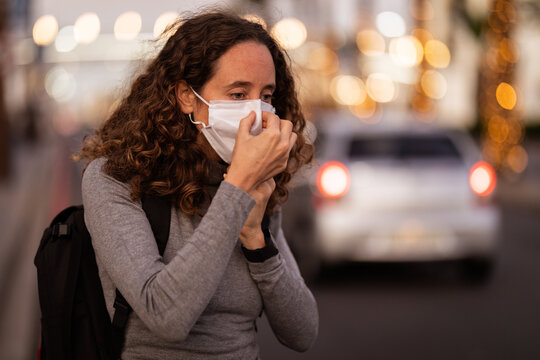Caucasian woman putting on a protective mask in the streets